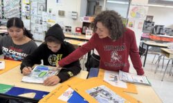 Ms. Angela Vennochi-Reid examines a student's end-of-year art work.